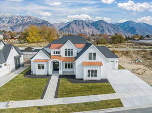 Modern farmhouse featuring board and batten siding, a standing seam roof, driveway, a mountain view, and metal roof