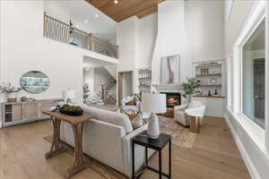 Living room with stairs, a towering ceiling, a large fireplace, and light wood-style floors