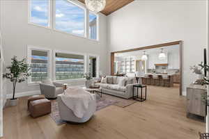 Living room featuring light wood-type flooring, an inviting chandelier, and high vaulted ceiling