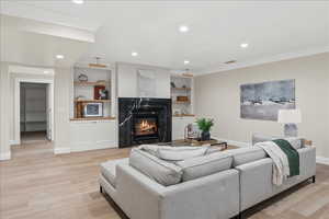 Living room with recessed lighting, a glass covered fireplace, light wood-style flooring, and baseboards