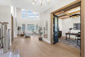 Interior space with a chandelier, beamed ceiling, baseboards, light wood finished floors, and a high ceiling
