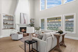 Living area featuring a healthy amount of sunlight, a towering ceiling, and light wood finished floors