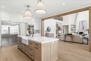 Kitchen featuring tasteful backsplash, a sink, light wood-style floors, built in appliances, and light stone countertops
