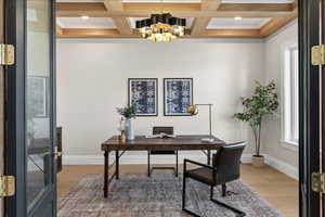 Home office with an inviting chandelier, light wood-style floors, beamed ceiling, and baseboards