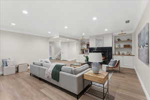 Living area featuring recessed lighting, a warm lit fireplace, stairs, and baseboards