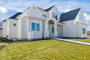 Modern inspired farmhouse with board and batten siding, a standing seam roof, a front yard, and metal roof