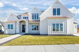 Modern inspired farmhouse featuring board and batten siding, a front yard, and a standing seam roof