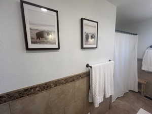 Full bath with tile walls, curtained shower, and tile patterned flooring