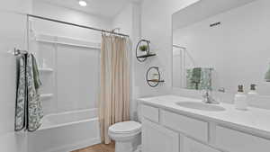 Full bathroom featuring wood finished floors, shower / bathtub combination with curtain, toilet, vanity, and visible vents