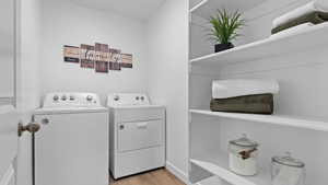 Clothes washing area with washer and dryer, laundry area, and light wood-style floors