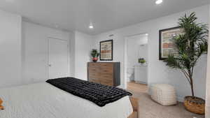 Bedroom featuring recessed lighting, visible vents, light colored carpet, and ensuite bathroom