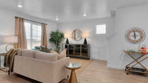 Living room featuring light wood-type flooring, a wealth of natural light, and baseboards