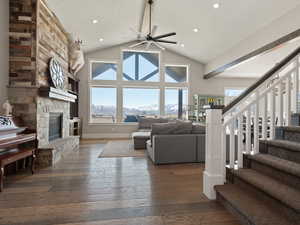Living area featuring hardwood / wood-style flooring, ceiling fan, a fireplace, stairway, and high vaulted ceiling