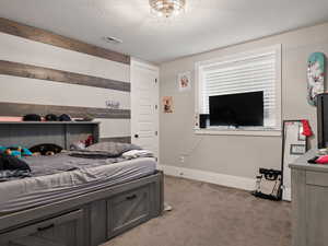 Carpeted bedroom featuring a textured ceiling, visible vents, and baseboards
