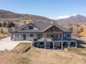 Rear view of house with a lawn, board and batten siding, a shingled roof, and a deck with mountain view