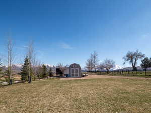 View of yard with fence, a storage unit, a mountain view, and an outdoor structure