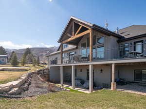 Rear view of property featuring a patio, a mountain view, board and batten siding, and a lawn