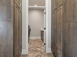 Clothes washing area featuring laundry area, brick floor, and baseboards
