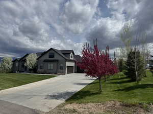 View of front of home featuring stone siding, driveway, board and batten siding, and a front yard