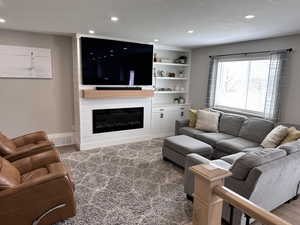 Living room with a glass covered fireplace, wood finished floors, recessed lighting, and visible vents