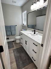 Full bath featuring visible vents, wood finished floors, toilet, and vanity