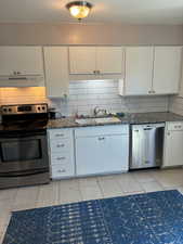 Kitchen featuring appliances with stainless steel finishes, white cabinetry, decorative backsplash, and wood finish floors