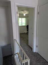 Hall featuring carpet, a textured ceiling, and an upstairs landing