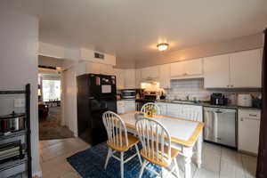 Kitchen with a sink, under cabinet range hood, visible vents, white cabinetry, and appliances with stainless steel finishes
