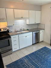 Kitchen featuring appliances with stainless steel finishes, white cabinets, decorative backsplash, extractor fan, and wood finish floors