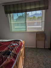 Bedroom with dark carpet and baseboards