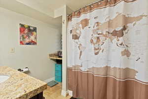 Full bath featuring a textured ceiling, curtained shower, baseboards, tile patterned floors, and vanity