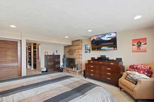 Bedroom featuring recessed lighting, a stone fireplace, and light carpet