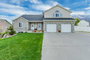 View of front facade featuring concrete driveway, a shingled roof, a front yard, fence, and a garage