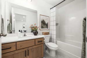 Bathroom featuring tile floors, toilet, vanity, and shower / tub combo