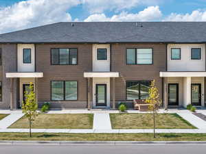 Multi unit property featuring a front lawn and roof with shingles