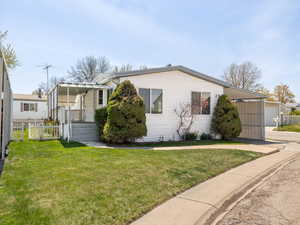 View of front of property featuring a front yard, concrete driveway, fence, and an attached carport