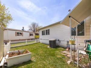 Rear view of house featuring fence, a lawn, and cooling unit