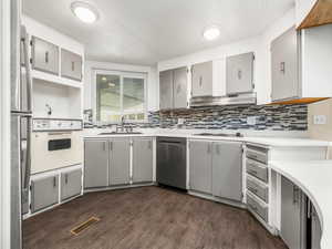 Kitchen with a sink, visible vents, white appliances, gray cabinets, and under cabinet range hood