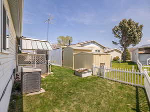 View of yard featuring fence private yard, an outbuilding, central AC, and a shed