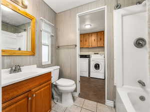 Bathroom featuring washing machine and dryer, tile patterned floors, vanity, and toilet