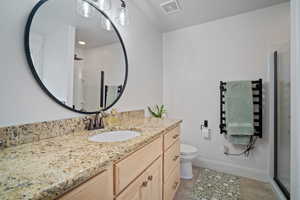 Bathroom with vanity, toilet, a stall shower, visible vents, and tile patterned flooring