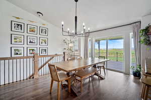 Dining space featuring vaulted ceiling, wood finished floors, and a chandelier