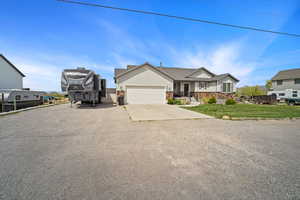 View of front facade with concrete driveway, stone siding, a garage, and a front lawn