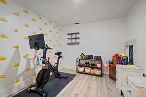 Workout area with baseboards and light wood-style floors