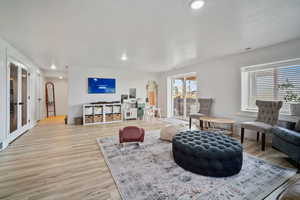 Living room with recessed lighting, wood finished floors, baseboards, visible vents, and french doors