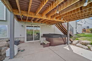 View of patio / terrace featuring an outbuilding, a storage unit, and a hot tub