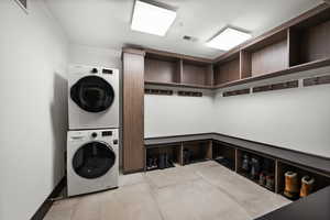 Washroom featuring baseboards, visible vents, stacked washer and clothes dryer, and laundry area