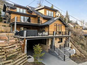 View of front of home featuring driveway, central AC unit, a balcony, and roof with shingles
