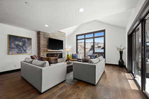 Living area with lofted ceiling, baseboards, dark wood-style floors, and a fireplace