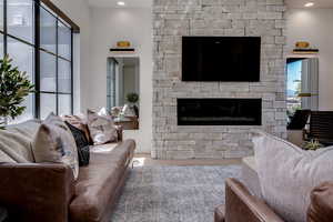 Living area with wood finished floors, recessed lighting, and a stone fireplace